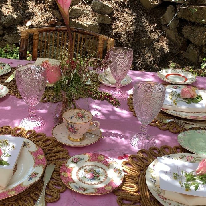 Elegant outdoor tea party table setting with pink linens and floral china