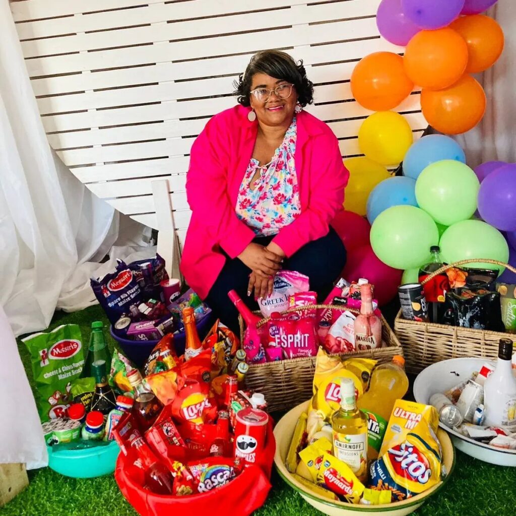 Woman sitting behind color-coordinated snack baskets and colorful balloons at a party.