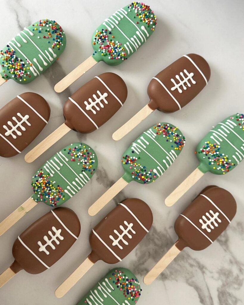 Football and football field themed cake pops on a white marble background