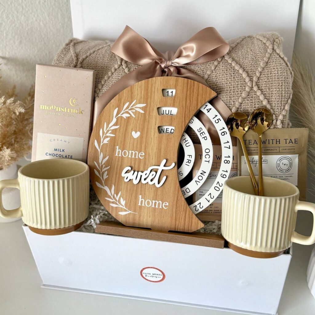 Gift box for new homeowners with mugs, a home sweet home plaque, and blanket.