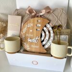 Gift box for new homeowners with mugs, a home sweet home plaque, and blanket.