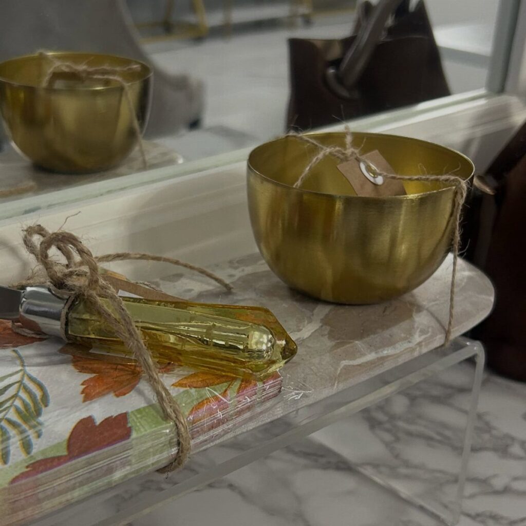 Gold metal bowls and floral napkins tied with twine as gift sets.