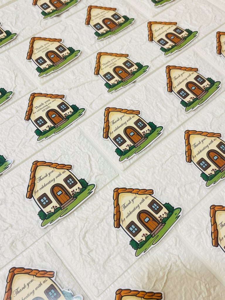 House-shaped paper tags with handwritten messages arranged on a white textured background.