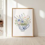 Framed art print of wildflowers in a teacup leaning against a white wall