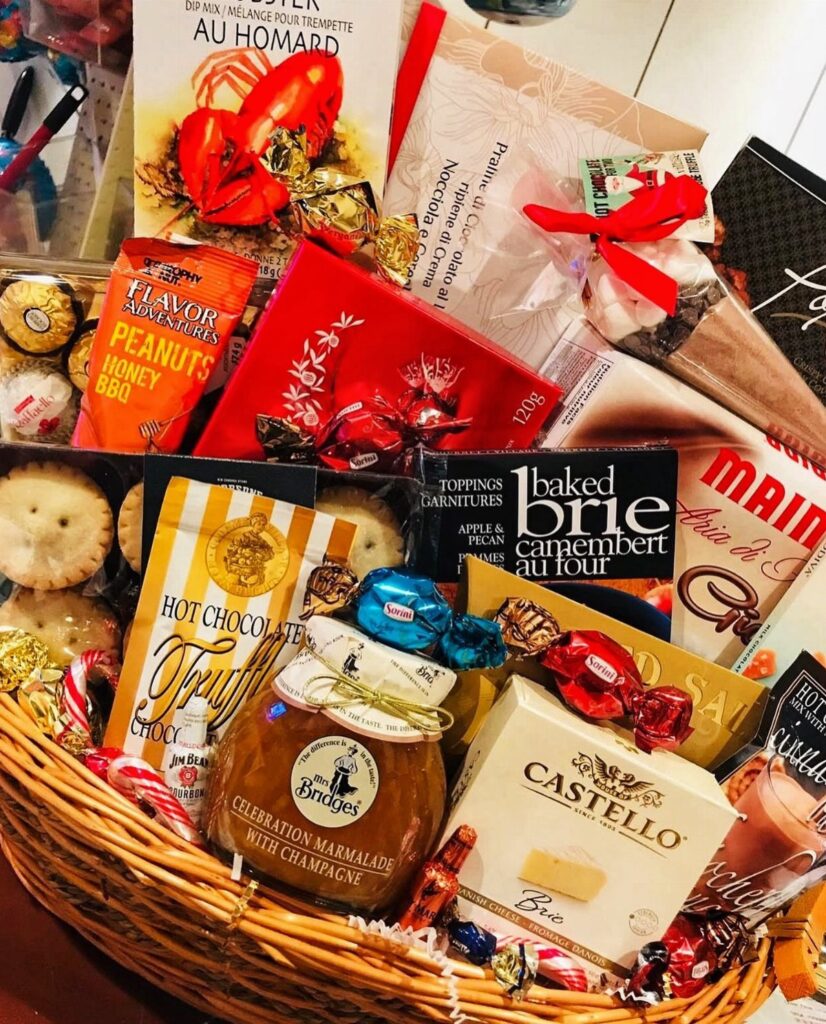 Wicker gift basket filled with gourmet cheeses, marmalade, chocolates, and a cookbook.