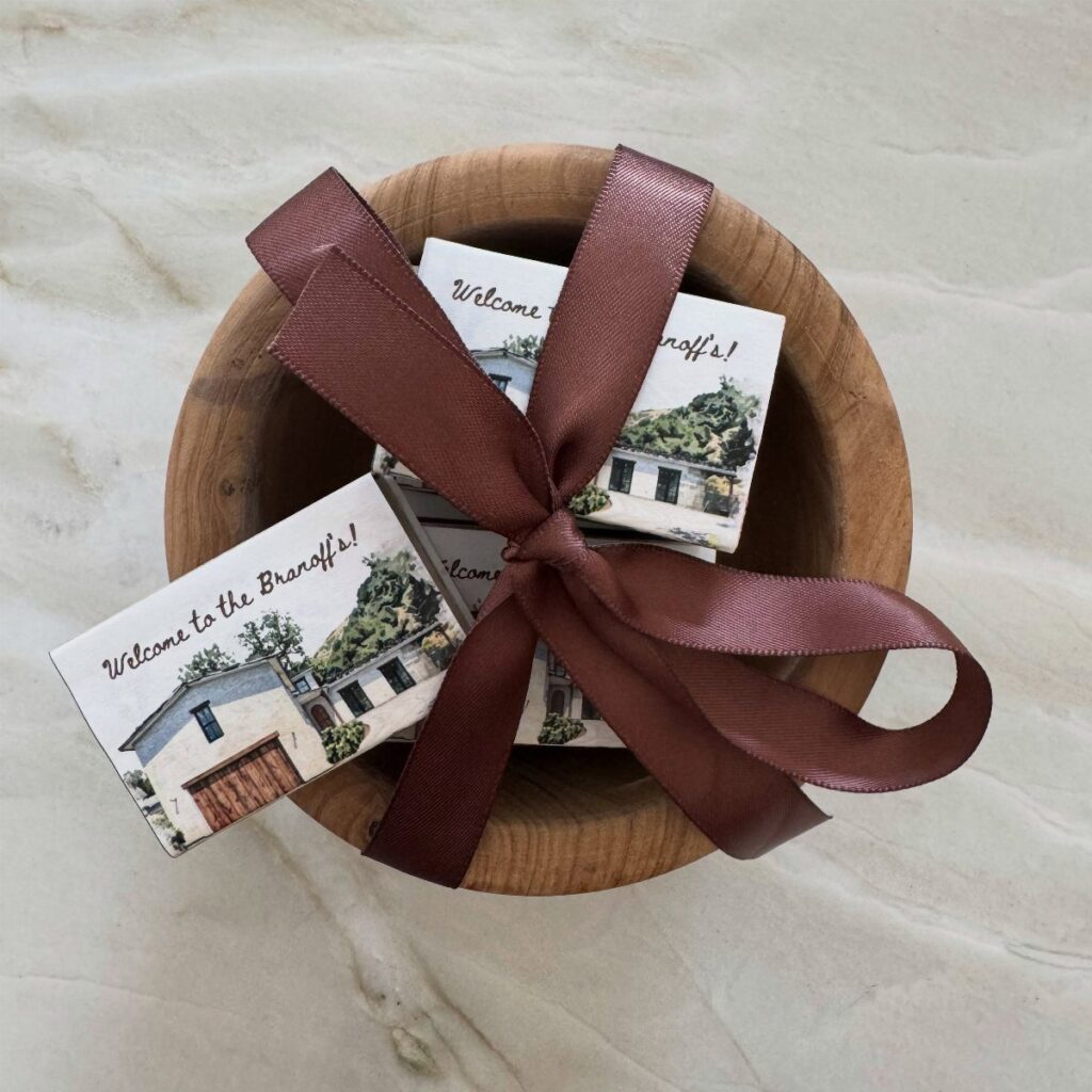 Personalized house coasters in a wooden bowl tied with a brown satin ribbon.