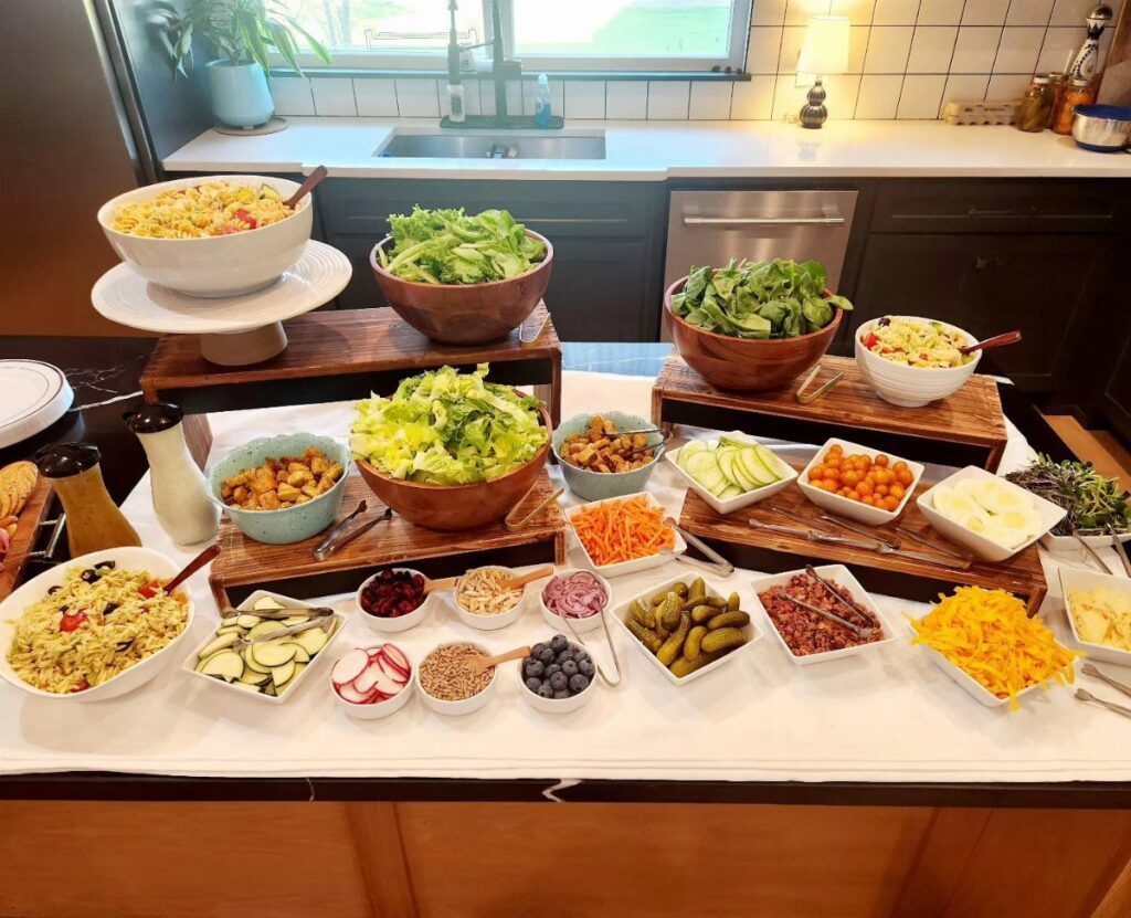 Salad bar with various bowls of greens, vegetables, and grains on a table.
